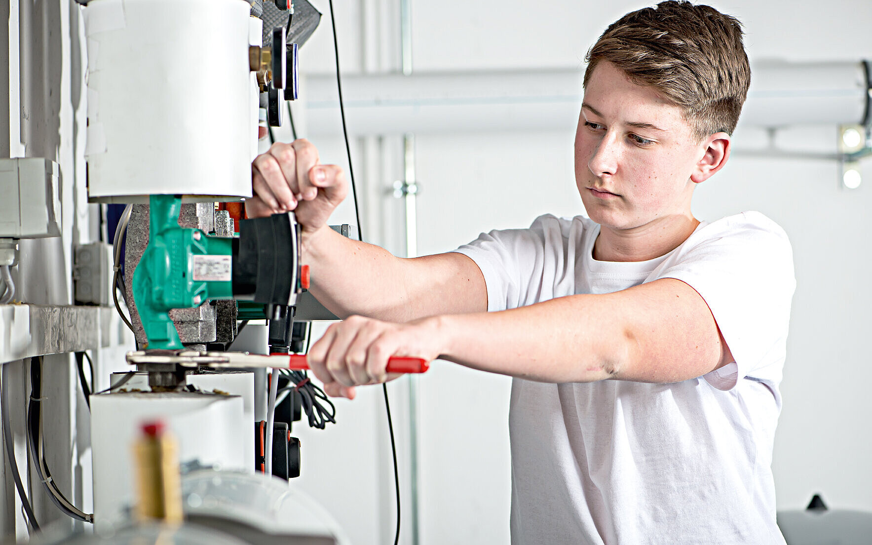 Auszubildender Anlagenmechaniker SHK repariert Heizungsanlage
